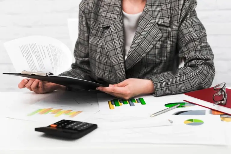 Contadora revisa documentos con calculadora y gráficos: beneficios de la contabilidad externa en Chile