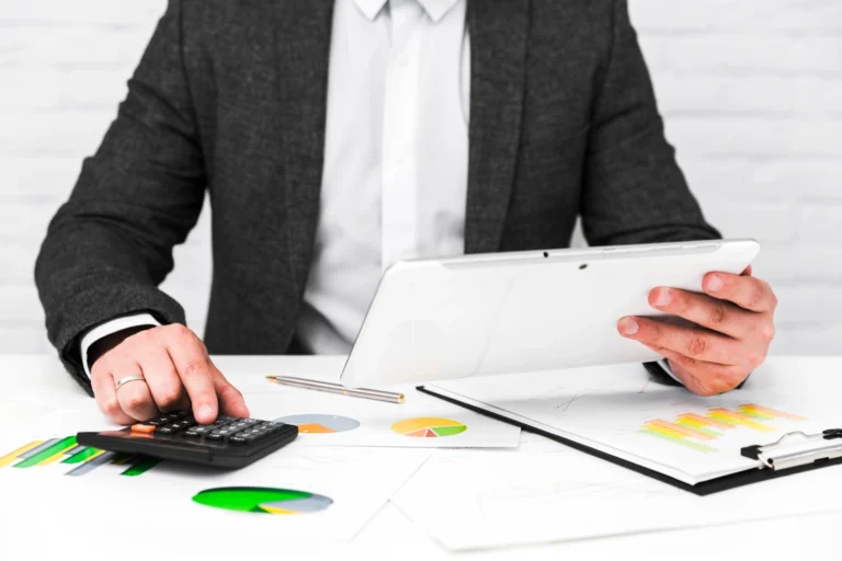 Auditor con calculadora y tableta revisa gráficos financieros: servicio de auditoría forense en Chile